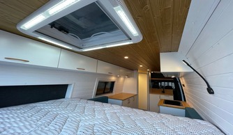 Interior moderno y acogedor de una camperización Baovan con cama amplia y claraboya