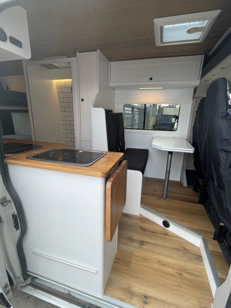 Vista lateral de la cocina y zona de descanso en la furgoneta Camper Peugeot Boxer L3H2 4+4.