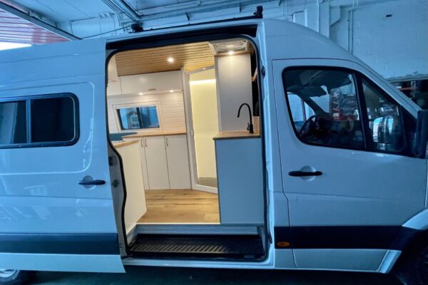 Mercedes Sprinter L4H2 Camper para 3 con Garaje con vista lateral, puerta abierta, espacio e iluminación.