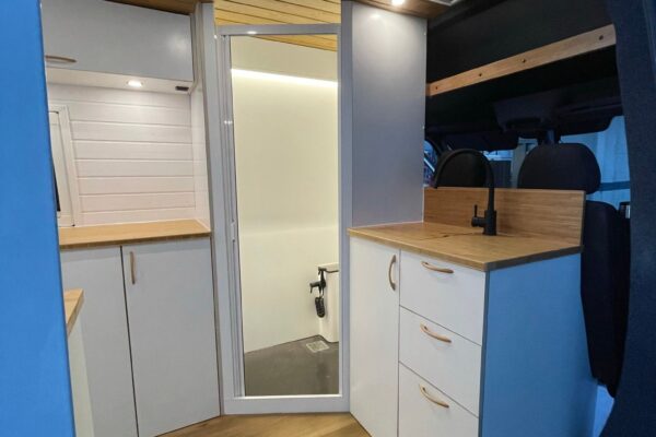 Mercedes Sprinter L4H2 Camper para 3 con Garaje con interior blanco y espacioso, cocina completa, armarios y baño completo.