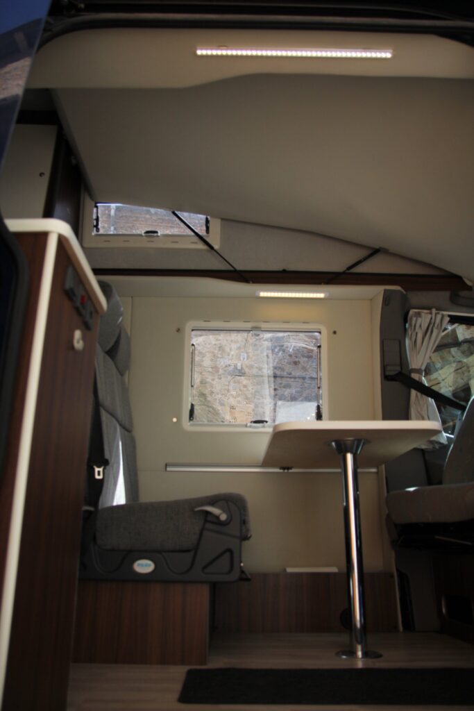 Detalle interno de la furgoneta VW Crafter con amplia área de esparcimiento y mesa por Baovan Camper.