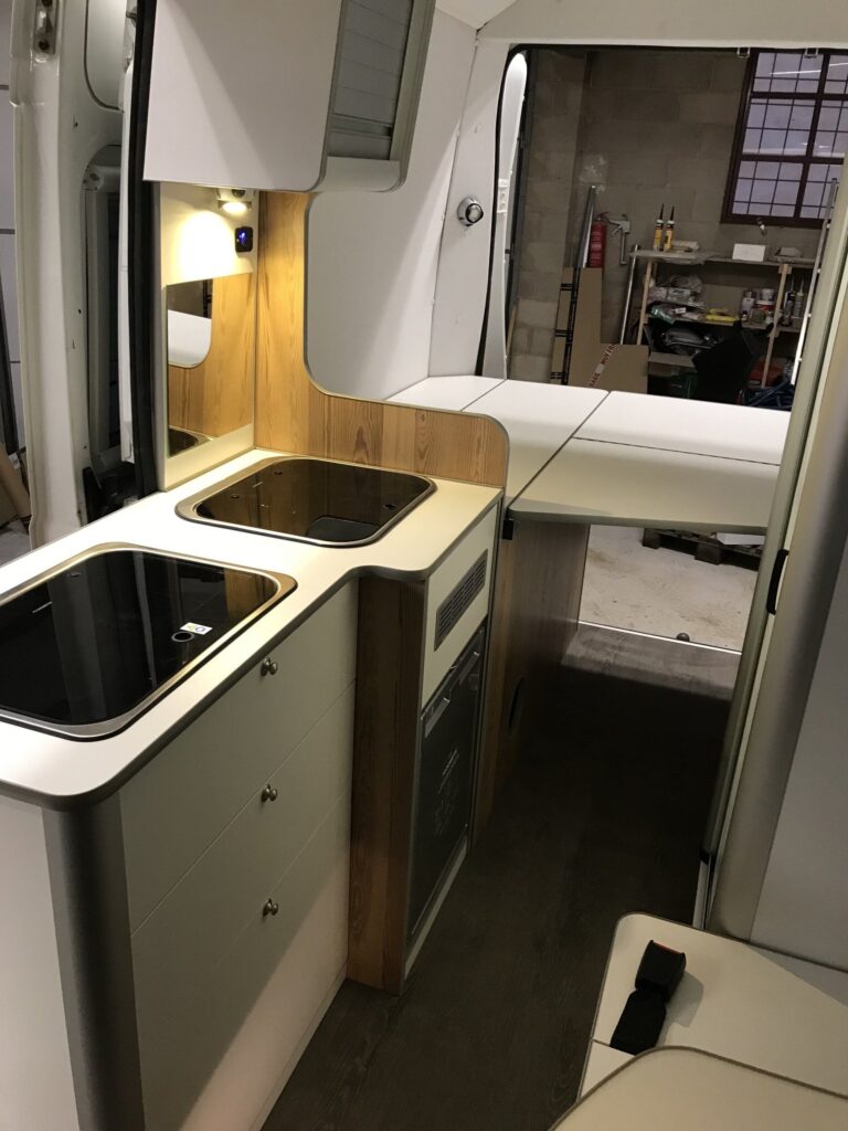 Detalle de la cocina con vista a la cama en la parte trasera, espacio y comodidad en la Camper Peugeot Boxer L2H2 4+2 de Baovan Camper.