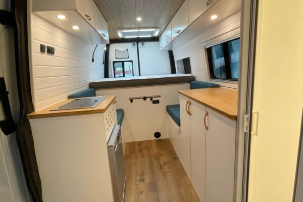 Vista completa del interior de la Mercedes Sprinter L4H2 Camper para 3 con Garaje, mostrando superficies y armarios.