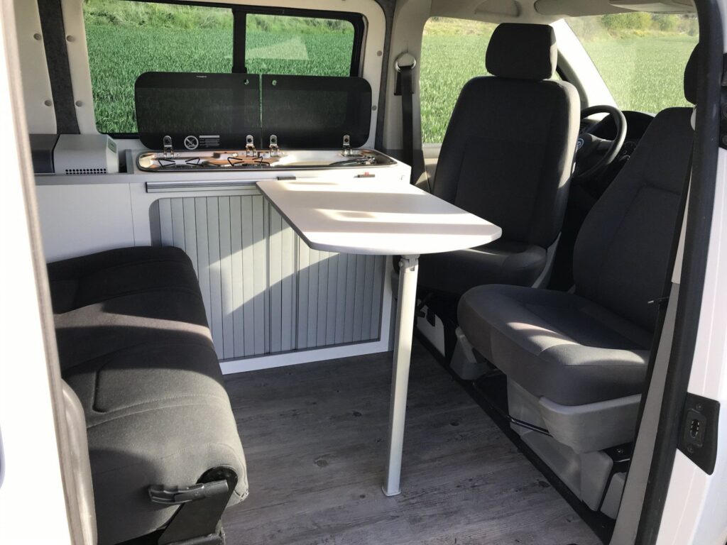 Detalle de las mesas extendidas y los bancos girados en la Volkswagen Transporter T5: espacio de descanso con 4 asientos