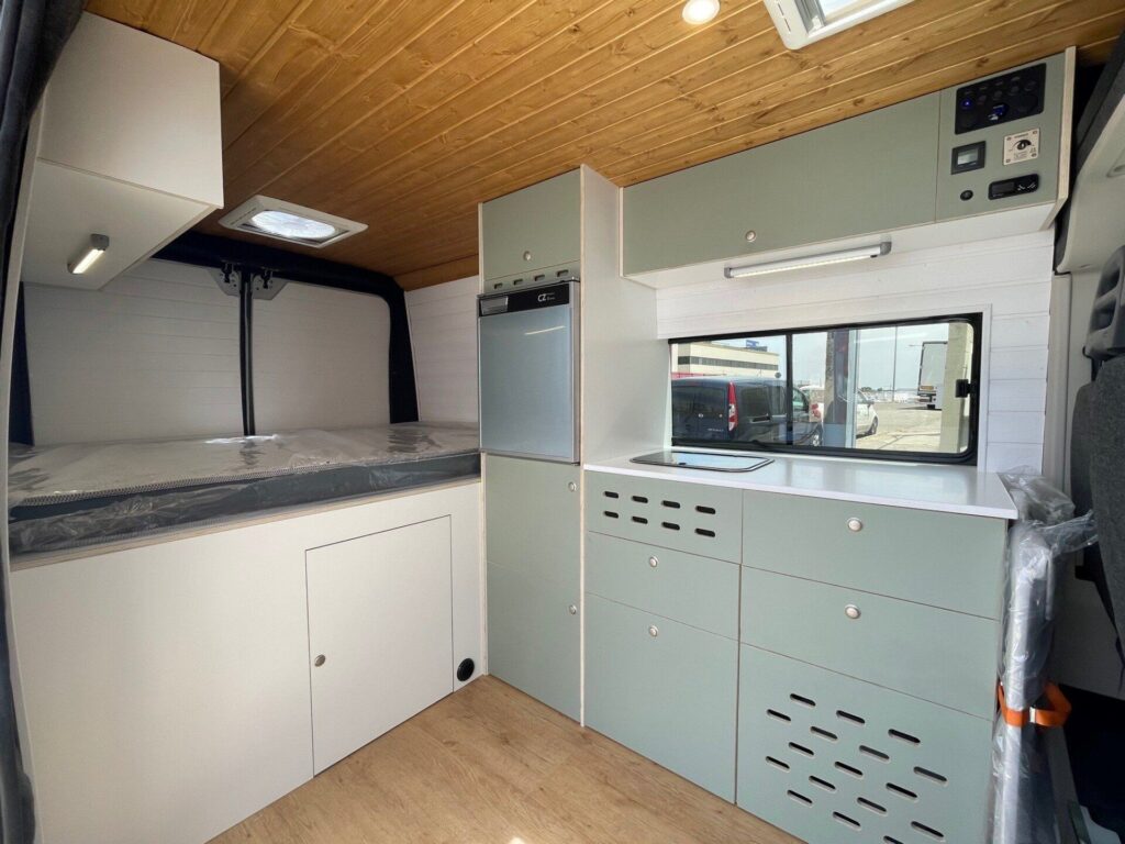 Vista del espacio interior con la amplia cocina y la cama en la Camper Citroen Jumper 3+2.