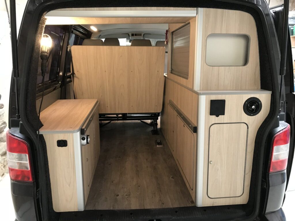 Cama desmontada en la Camper Volkswagen Transporter T5 convertida por Baovan, con acceso al espacio optimizado y armarios.