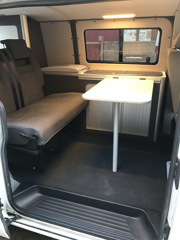 Detalle del espacio de descanso montado con mesa plegable abierta en la furgoneta Camper VW Transporter T5 4Motion