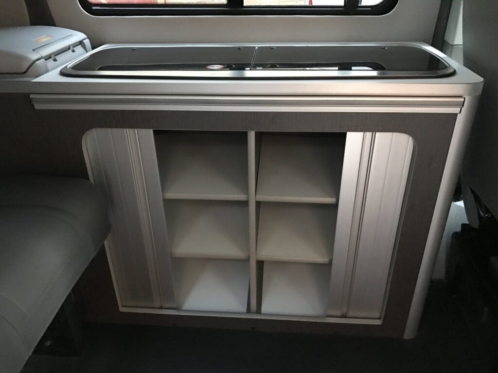 Detalle del armario con mucho espacio de almacenamiento, incluyendo estanterías, en la furgoneta Camper VW Transporter T5 4Motion
