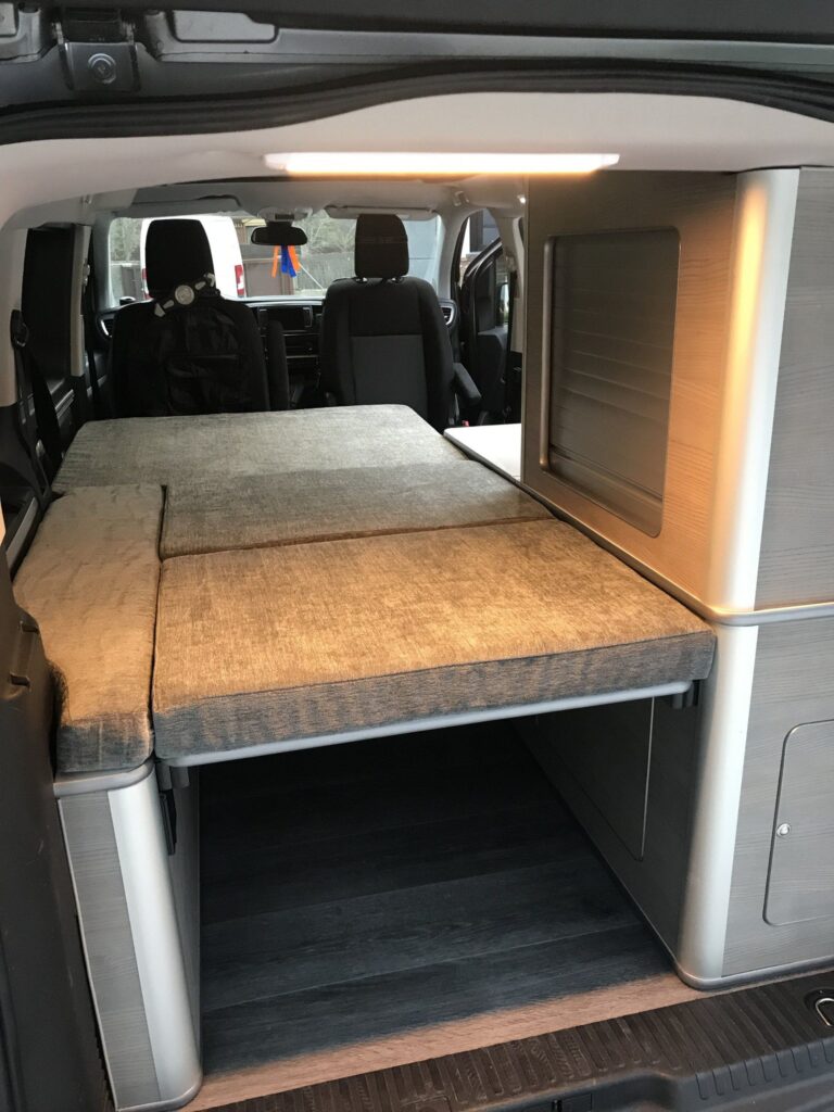 Detalle de la cama montada en la Peugeot Traveller: interior, espacio para guardar cosas debajo