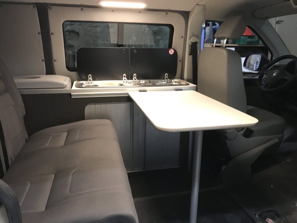 Detalle de la zona de descanso con mesa abierta en la furgoneta Camper VW Transporter T5 4Motion