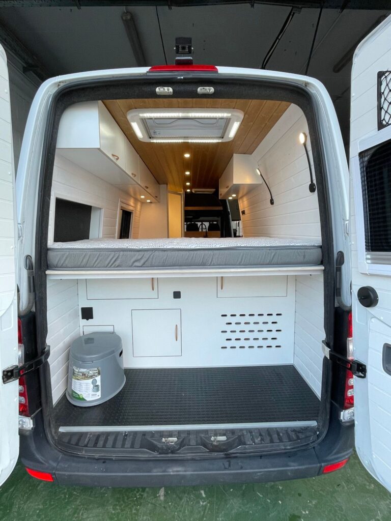 Mercedes Sprinter L4H2 Camper para 3 con Garaje con puerta trasera abierta, mostrando gran espacio de almacenamiento debajo de la cama.