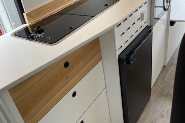 Detalle de la cocina, con nevera, fregadero y cajones en la Citroën Jumper L4H3 4+4, convertida por Baovan Camper.