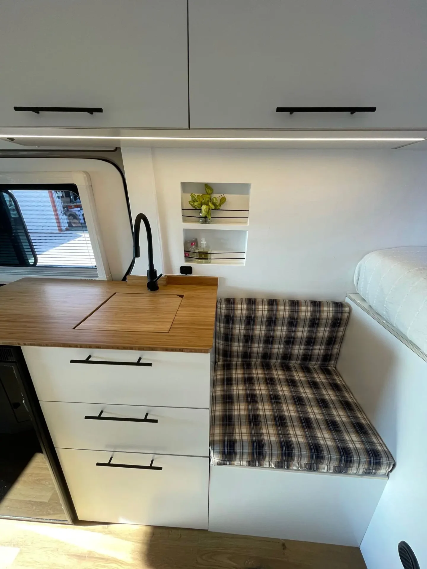 Camper VW Crafter L4H2 con mesa plegable, espacios de almacenamiento, fregadero y ventana.