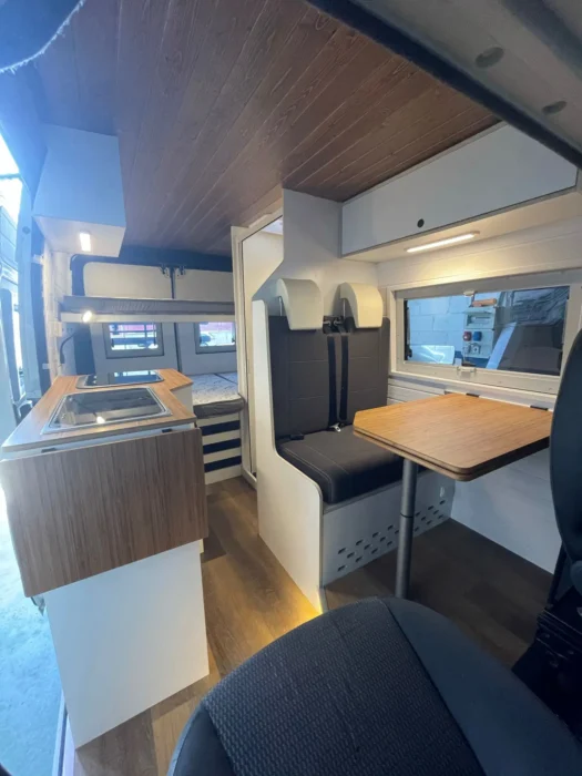 Perspectiva del interior de la Peugeot Boxer Camper desde la cabina, mostrando la armonía entre la zona de vida y la cocina funcional.