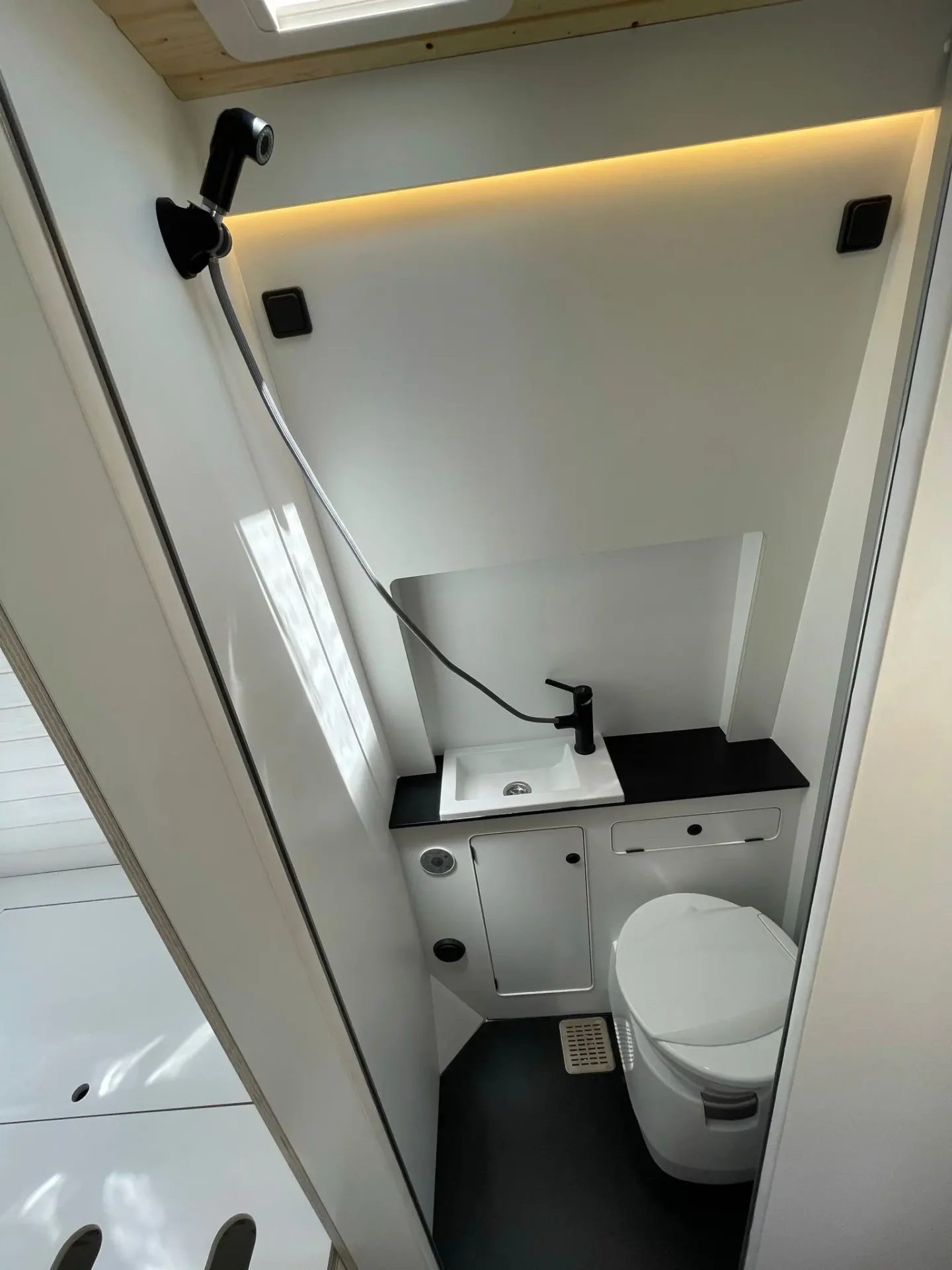 Compacto y funcional baño dentro de la furgoneta camper Ducato L4H3, con inodoro, lavabo y almacenamiento integrado, optimizado para viajes largos.