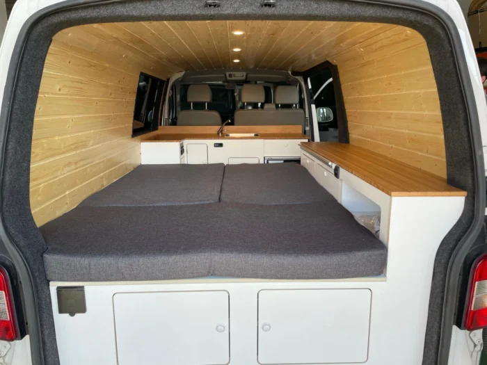 Vista desde la puerta trasera de la VW T6 Camper con la cama completamente extendida.