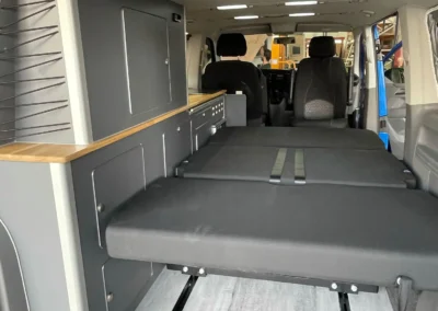VW T6 Camper con cama plegable abierta, comodidad y espacio.