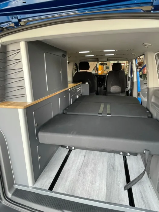 VW T6 Camper con cama plegable abierta, comodidad y espacio.